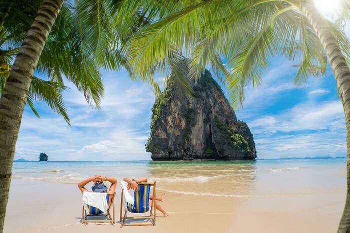 A couple relaxes on a beach in the Phang Nga Bay on one of the best islands in Thailand for honeymoon