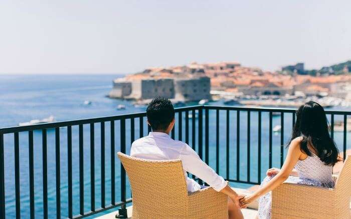 A couple sitting on a balcony with sea view