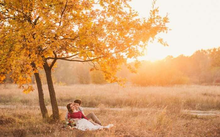 Couple romancing under a maple tree in autumn