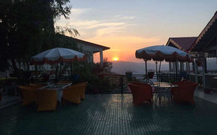 Seating area of Maple Resort overlooking a setting sun in Chail