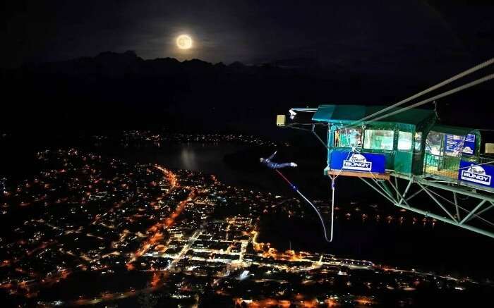 A man performing a bungee jump at night in Queenstown in New Zealand