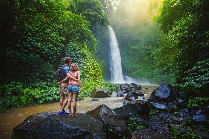 A couple looking at the gorgeous waterfall in the rainforests of Malaysia