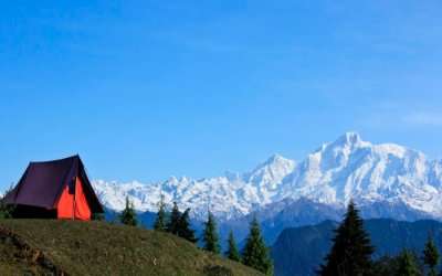 A camp perched at the top overlooking snow capped mountains in Uttarakha