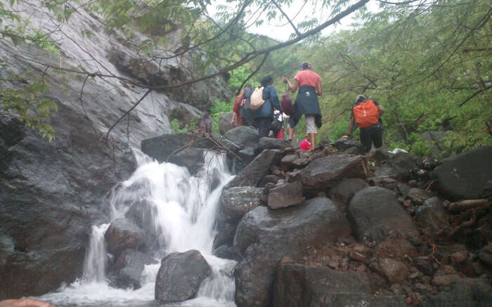 People trekking through a small waterfall 