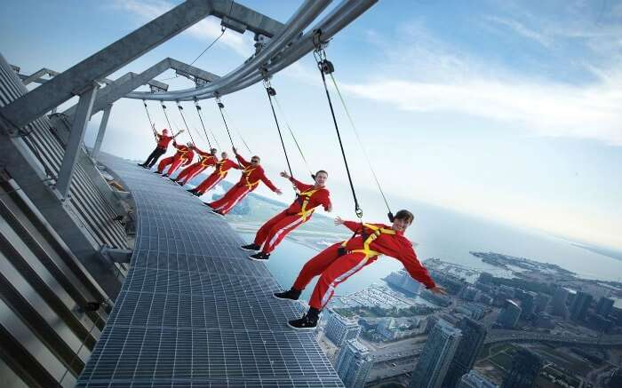 People wearing red clothes hanging from Macau Tower