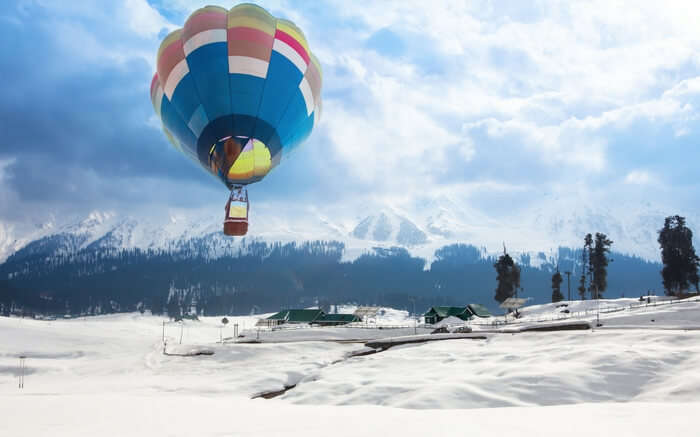 A hot air balloon flying over a village in Gulmarg in winter