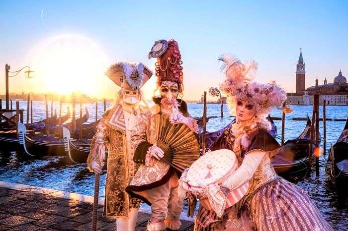 Venetian costumes pose in front of gondolas during the Venice Carnival days. The most famous festival in the world.