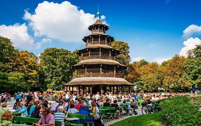 People sitting in a gorgeous garden with a huge pagoda like structure 
