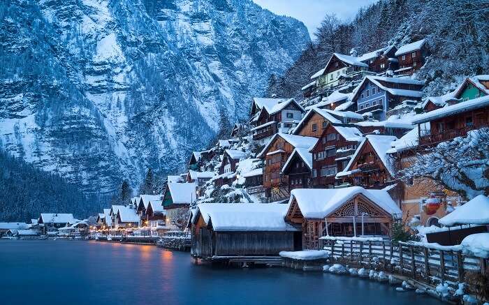 snow covered homes by a lake in austria 