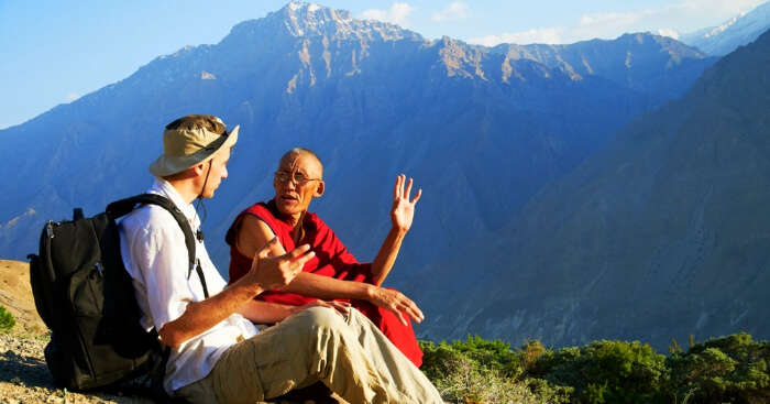 a monk sitting with a tourist