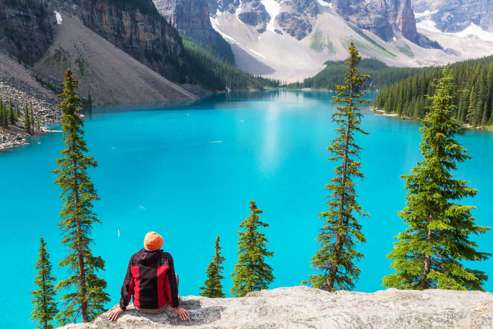 a woman sitting on rock over looking a gorgeous lake in Banff National Park