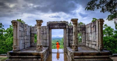a monk standing at a ruined structure