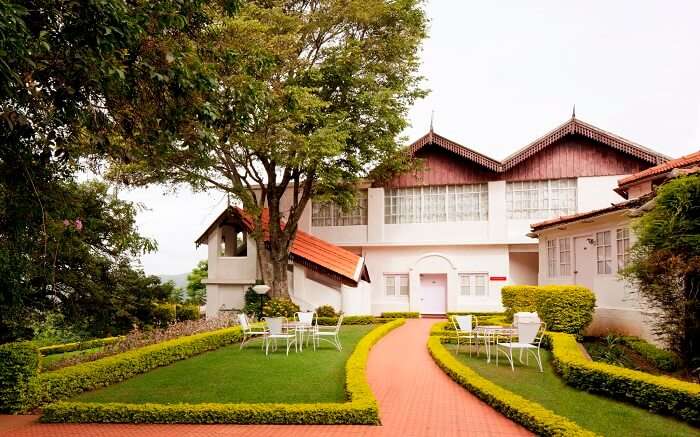 a white beautiful hotel in Coonoor with manicured lawn 