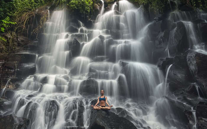 a women doing yoga in front of a waterfall ss11052018