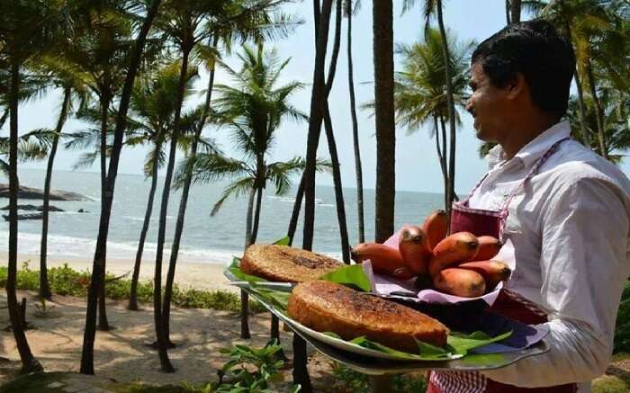 helper at Chera Beach Resort carrying freshly made food