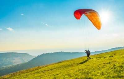 A person ready to paraglide from a hillside