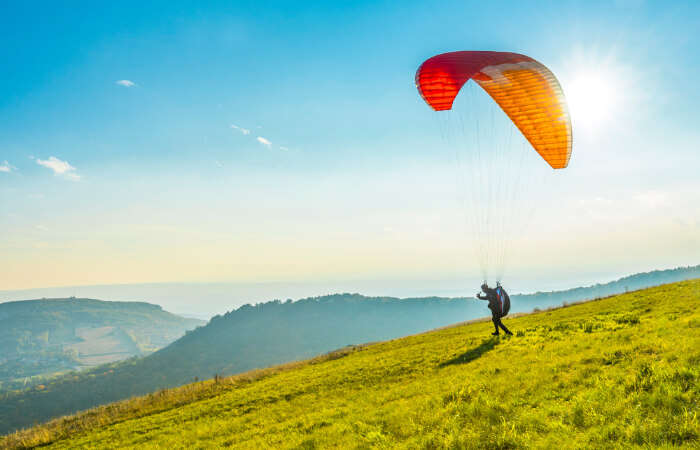 A person ready to paraglide from a hillside