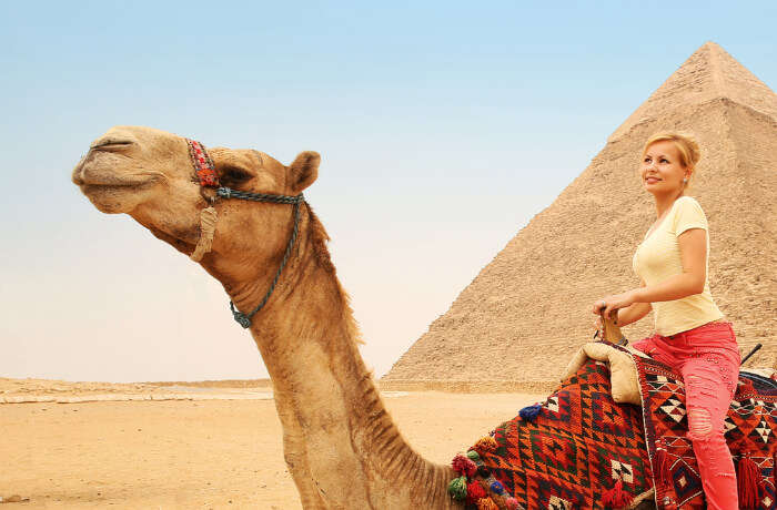 A woman on a camel near a pyramid inn Egypt