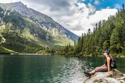 A backpacker sitting on a rock near a Poland lake
