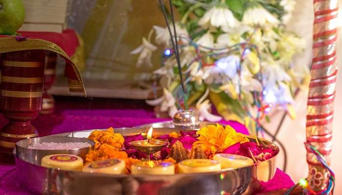 Pooja Thali including lamps, flowers, and incense.