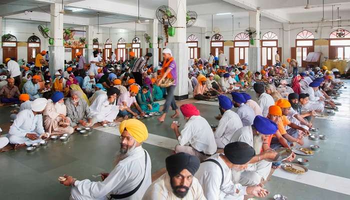 People sitting on the floor and eating the langar