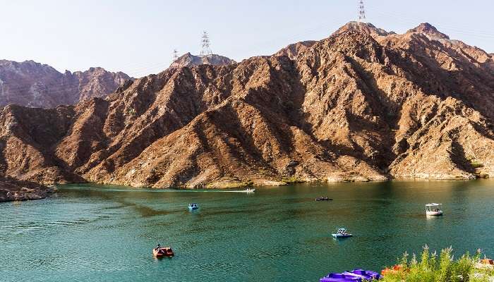 A view of mountains surrounding Al Rafisah Dam, where people are seen kayaking