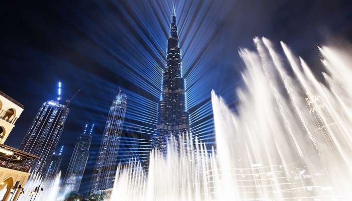 The panoramic view of one of Dubai iconic buildings, Burj Khalifa with a fountain show at night. 