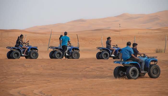A group of friends indulging in a thrilling Dubai desert quad ride for fun experience