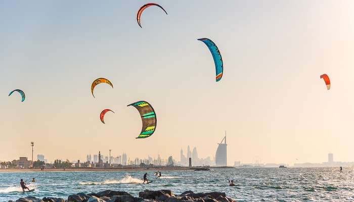 A view of people indulging in kite surfing while witnessing Dubai sunset