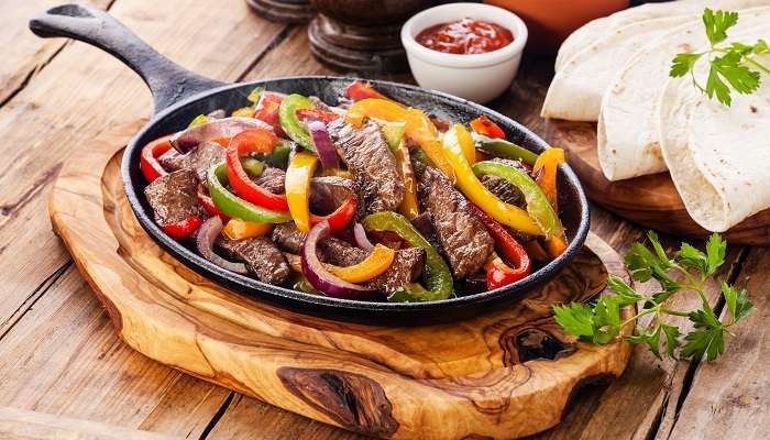 Beef Fajitas with colourful bell peppers, tortilla bread, and success in the pan, the delectable Mexican food in Abu Dhabi.