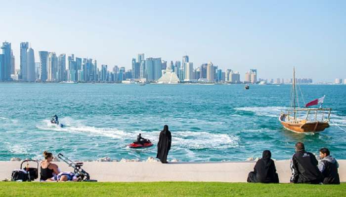 At one of the famous places to visit in Qatar, MIA Park, people are chilling out by the edge of the bank and some doing jetskis. 
