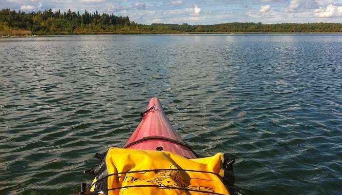 A breathtaking scene of a kayak floating on Garner Lake, located in one of the small towns in Alberta, Smoky Lake