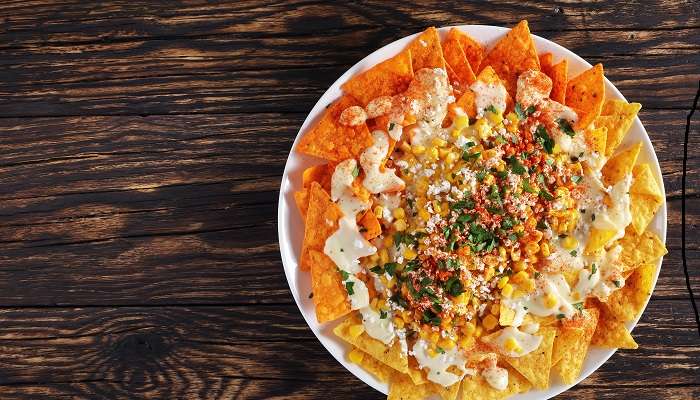 Crunchy spicy nachos or Tortilla chips with toppings of crumbled cheese, cilantro, and more at one of the Mexican restaurants in Abu Dhabi, Taqado Mexican Kitchen.