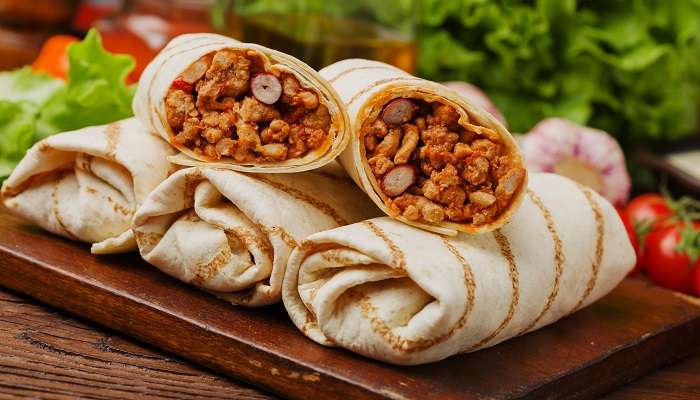 Burritos wraps served with meat, beans, and vegetables on the wooden board at one of the vibrant Mexican restaurants in Abu Dhabi, Tortilla.