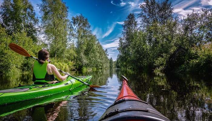 A woman kayaking on a sunny day in the small river Savaron, Umea, one of the charming small towns in Sweden.