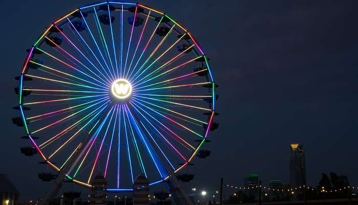 Enjoy the ferris wheel adorned with rainbow-coloured neon lights at amusement parks in Oklahoma