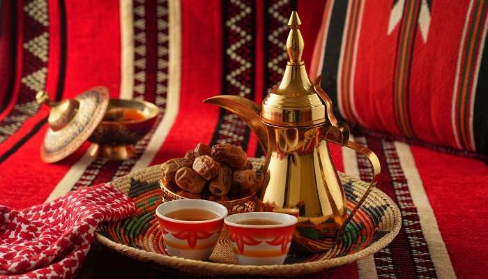 Café arabe avec Dallah doré sur fond rouge foncé,