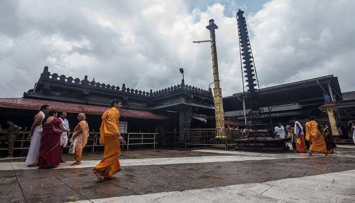Group of devotees in traditional attire at Mookambika temple offering prayers.