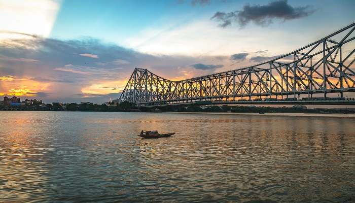 Howrah Bridge iconic cantilever over Hooghly, framed by sunset.
