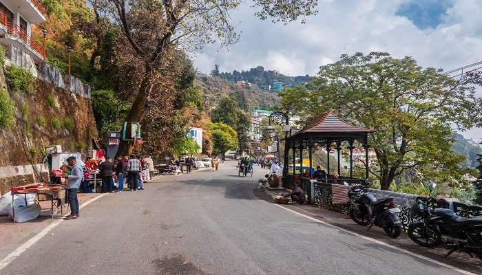 Tourists strolling on the famous Mall Road in Mussoorie during daytime while on their Delhi to Mussoorie road trip.
