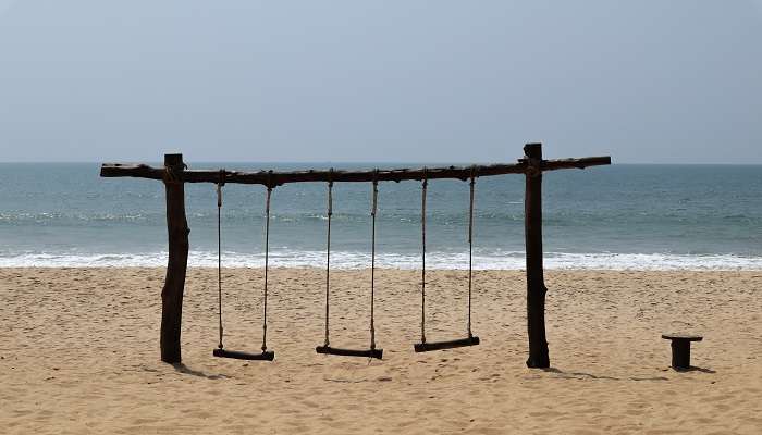 Wooden swings on the sands of the Padubidri Beach, one of the best beaches in Udupi