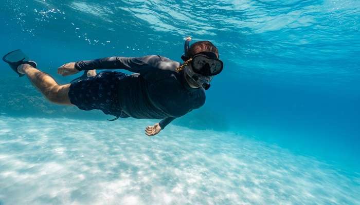 Young man snorkeling in clear, vibrant waters in Phuket. 