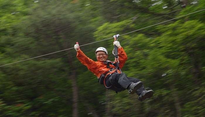  a man soar through the air on Zipline in Bangkok