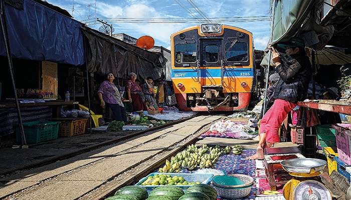 Train crosses the local streets full of various stalls with food and other items for sale