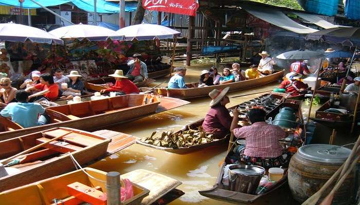 Several tourists prefer visiting the floating market in a boat. 