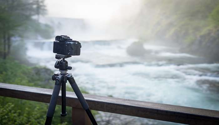 A photographer capturing serene waterfall image