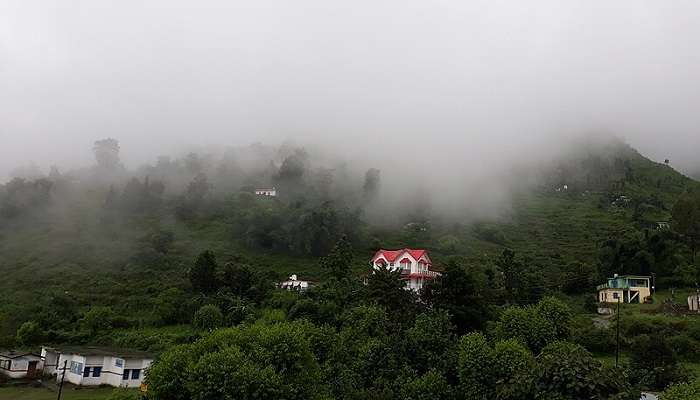 A mystical view of a village near Naukuchiatal, surrounded by a lush green area
