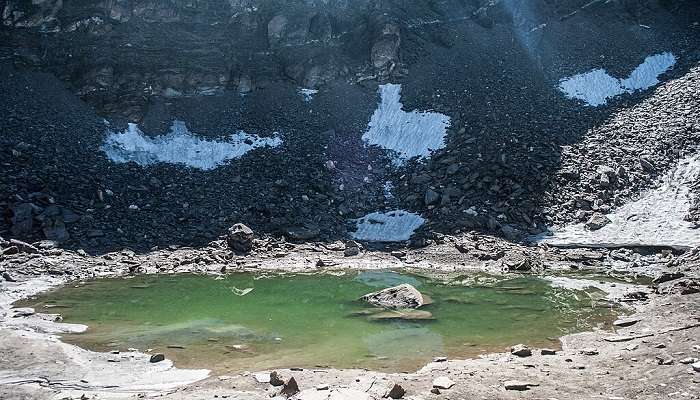 Roopkund Lake with high cliffs to visit in Peora.