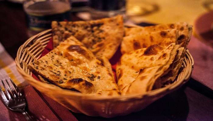 Basket of cooked Tandoori Naan on a table.