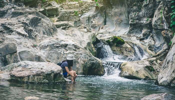 A woman is watching the cascading Kolapathana waterfall 